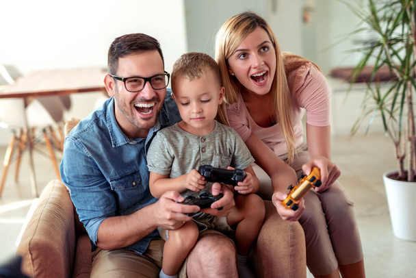 Boldog család játszik videojátékok otthon, és jól érzik magukat együtt. - Fotó, kép