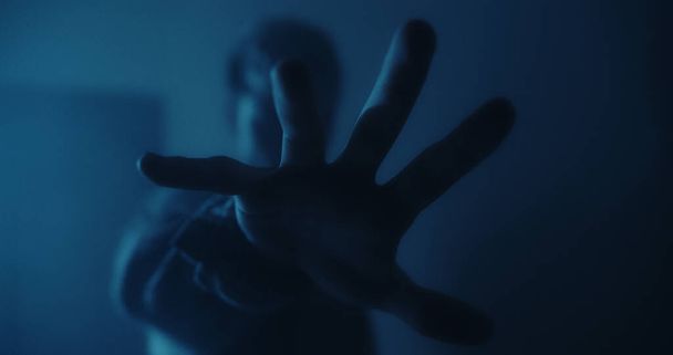 Zbliżenie dłoni mężczyzny do zamazanego ciemnoniebieskiego zaplecza - Zdjęcie, obraz