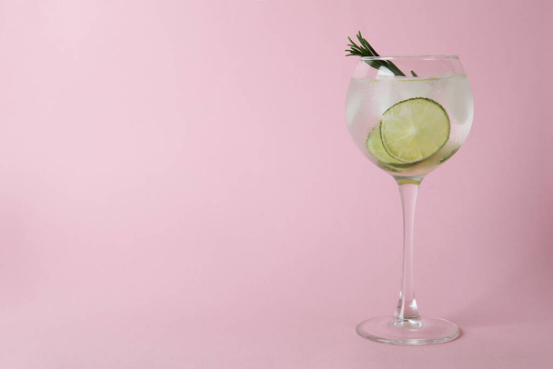 Glass of cocktail with lime on pink background - Foto, imagen
