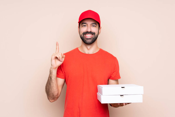Fiatal férfi kezében egy pizza felett elszigetelt háttér rámutatva egy nagyszerű ötlet - Fotó, kép