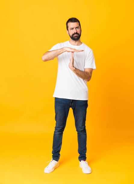 Полнометражный снимок человека с бородой на изолированном желтом фоне, делающий тайм-аут - Фото, изображение