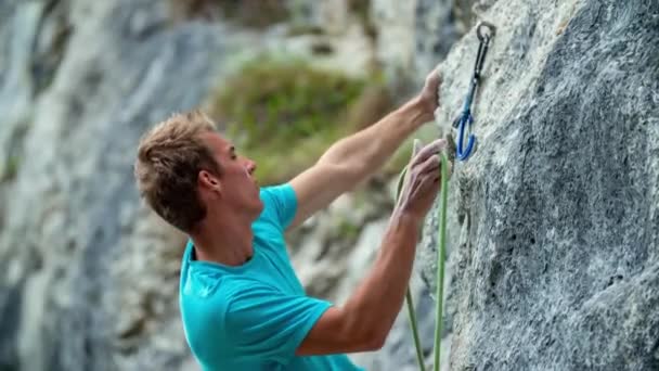 Jovem forte caucasiano menino alpinista stands, unclips e segura a montanha, close-up - Filmagem, Vídeo