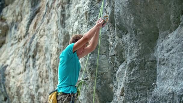Mladý atletický muž cvičí horolezectví na strmé vysoké stěně s provazy a dalším vybavením. - Záběry, video