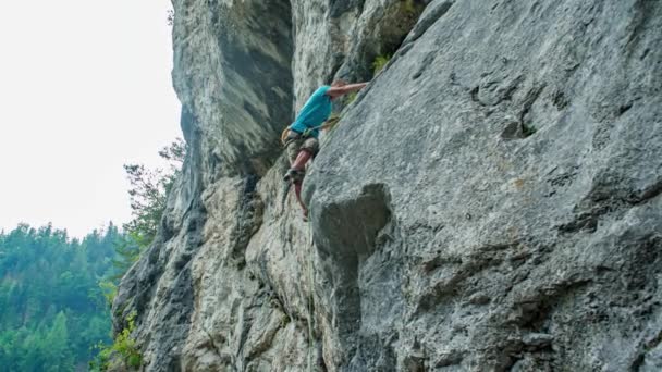 joven hombre pro escalador de roca asciende a un acantilado vertical. Amante del riesgo y desafío - Metraje, vídeo