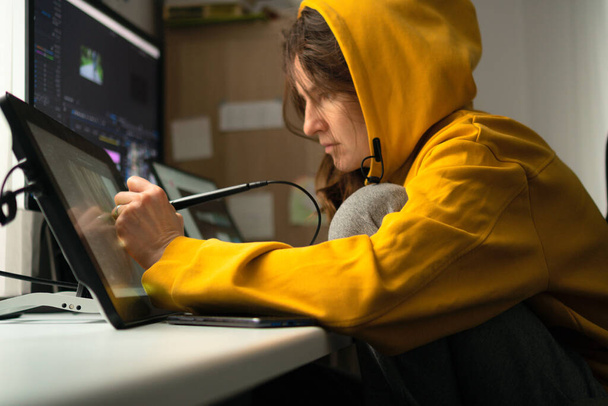 A young female student sitting at the table, using graphics tablet. Woman working from home. Concept for distance learning or home office - Valokuva, kuva
