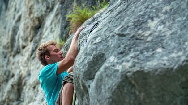 Lassú felvétel egy fiatal emberről, aki sziklát mászik egy nagy sziklán Burjakove Peciben, Szlovéniában. - Felvétel, videó