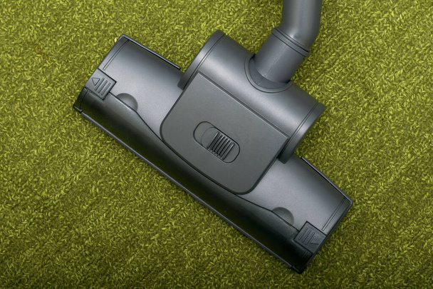 the turbo brush of the vacuum cleaner removes dust on the background of the green palace. High quality photo - Foto, Imagen