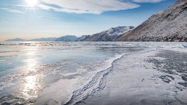 Long, sinuous cracks extend beyond the horizon on the dark, endless ice of Lake Baikal - Foto, imagen