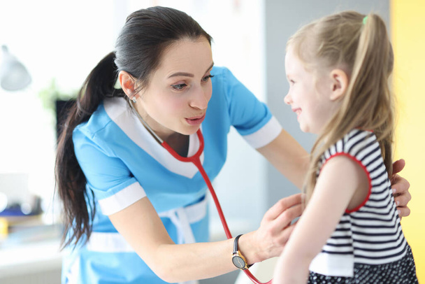 Woman doctor listening with stethoscope little girl in clinic - Photo, Image