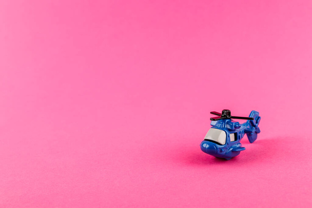 Small plastic helicopter with copy space on pink background. Toy. - Photo, image