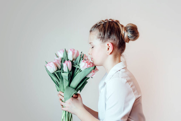 Beautiful young girl with a bunch of pink tulip flowers side view - Fotó, kép