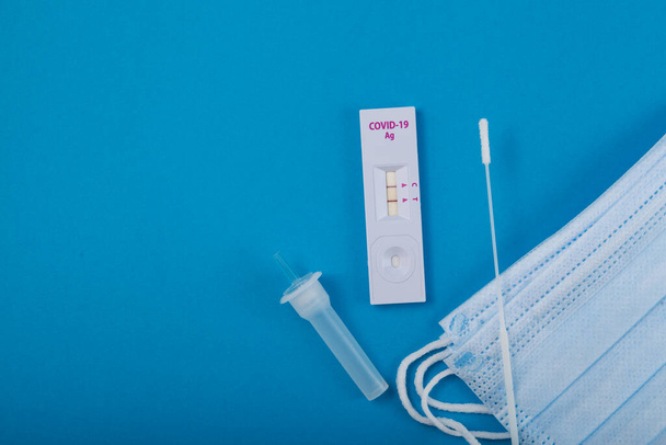Rapid test for Covid-19 Coronavirus, positive result. Laboratory kit for self-testing at home. Blue paper background, copy space. - Valokuva, kuva