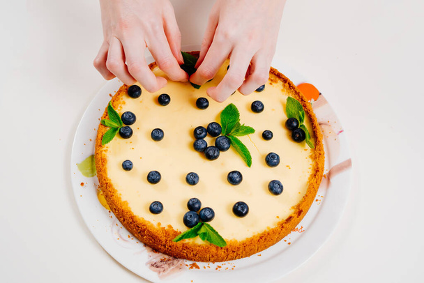 pastel de queso hecho en casa decoración de la mano con bayas de arándano y hojas de menta.  - Foto, Imagen