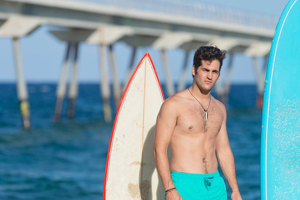 schöner und attraktiver Surfer im Neopren-Badeanzug mit Surfbrett, der nach dem Surfen cool posiert und Sommer-Wassersport und Urlaub genießt - Foto, Bild