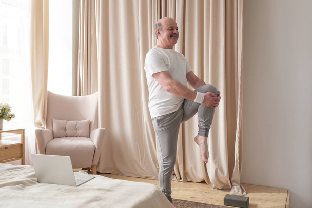 Senior handsome sportman doing stretching and balancing yoga exercise at home - Fotoğraf, Görsel
