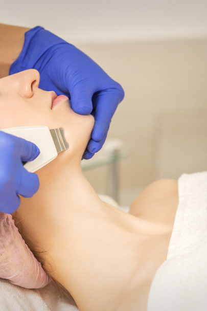 Mooie jonge vrouw ontvangen ultrasone cavitatie gezichtsreiniging in schoonheid spa salon - Foto, afbeelding