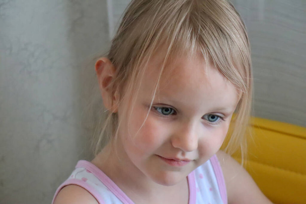 Portret małej uroczej blondynki w wieku 5 lat, zamyślony i patrzący w dół - Zdjęcie, obraz