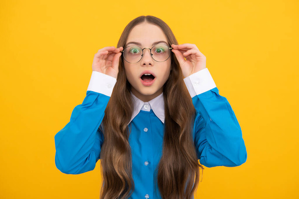 Impresionante niña de edad escolar en gafas con aspecto asombrado fondo amarillo, asombro. - Foto, Imagen