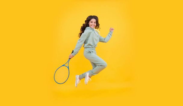 happy energetic child jump in sportswear with squash racquet on yellow background, sport success. - Zdjęcie, obraz