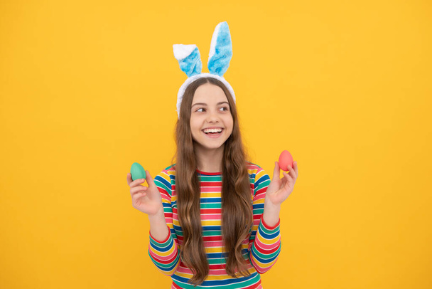 святкові привітання. щаслива дівчина-підліток носить вуха кролика. щасливого Великодня. щастя дитинства. дитина в кролячих вухах тримає пофарбовані яйця. час для розваги. чарівна смішна дитина на полюванні на яйце. Великоднє весняне свято
. - Фото, зображення