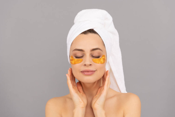 zmysłowa pani z ręcznikiem frotte używać twarzy złote oko przepaski na skórę, hydrożel. - Zdjęcie, obraz