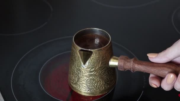 Frauenhände kochen türkischen Kaffee in Cezvar auf Herd. Schwarzer Kaffee kocht in Cezve. Schwarzer Rohkaffee kocht in der Türkei - Filmmaterial, Video