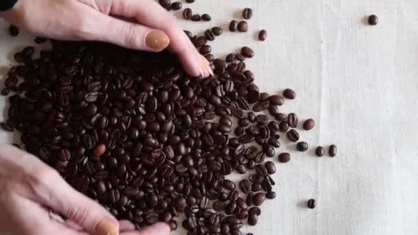 Main montrant les grains de café. grains de café frais torréfiés sur une surface sac chiffon - Séquence, vidéo