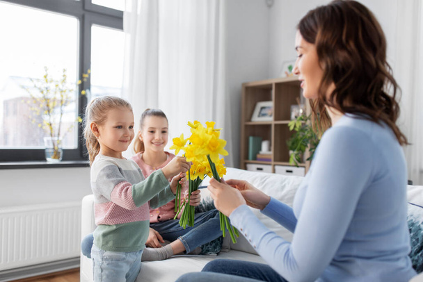daughters giving daffodil flowers to happy mother - Foto, Imagen