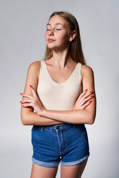 Portrait of calm teen girl with freckles posing with closed eyes and folded hands - Photo, image