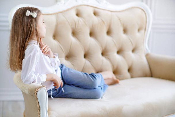 Pequena menina bonito encontra-se no sofá na sala - Foto, Imagem