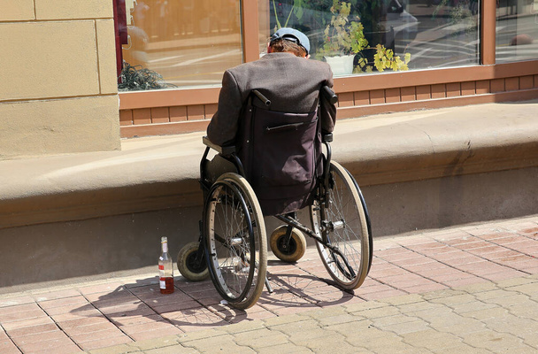 Dans la rue, une personne handicapée dort dans un fauteuil roulant après avoir bu de l'alcool. - Photo, image