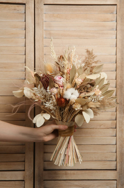 Woman holding beautiful dried flower bouquet on wooden background, closeup - Foto, afbeelding