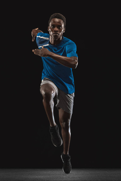 Μπροστά όψη του Αφροαμερικανού άνδρα, προπόνηση αθλητή απομονωμένη σε μαύρο φόντο. - Φωτογραφία, εικόνα