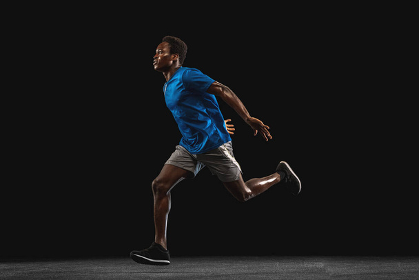 Un joven afroamericano, atleta aislado sobre fondo negro. - Foto, Imagen