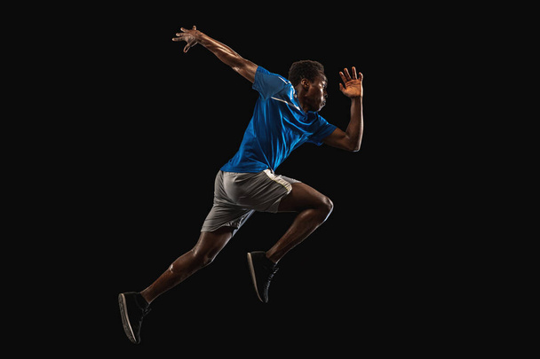 Молодой афроамериканец, спортсмен, тренирующийся на черном фоне. - Фото, изображение