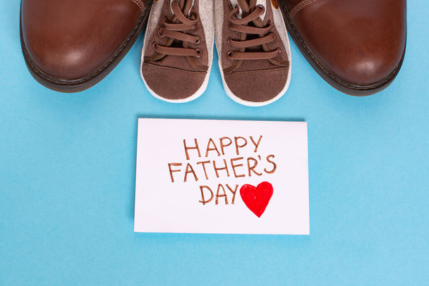 Fathers Day celebration. Big and small shoes on a wooden background. Father day composition - Foto, Imagem