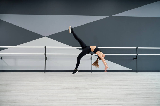 Woman doing wheel jump in dance hall. - Fotoğraf, Görsel
