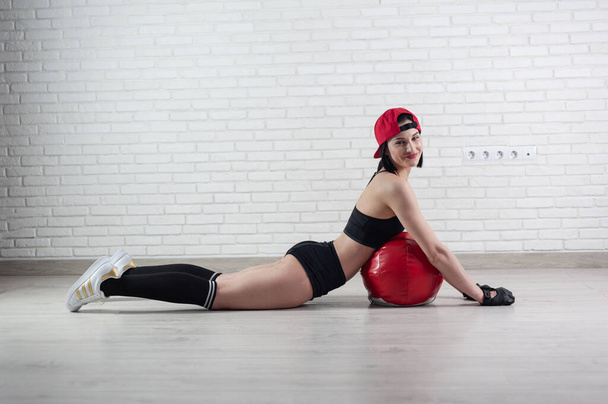 athletic strong woman in sportswear trains with a fitness ball on a light background - Zdjęcie, obraz