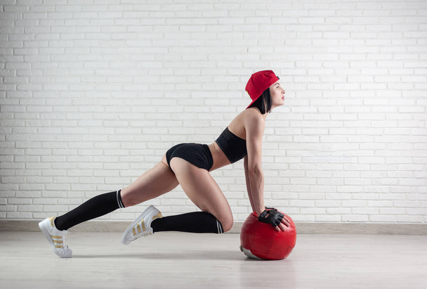 athletic strong woman in sportswear trains with a fitness ball on a light background - Photo, image