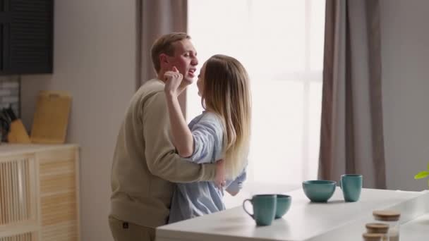 A young couple man and woman in the morning dance together to the music. A cheerful couple husband and wife flirt and dance in the morning in the kitchen - Footage, Video
