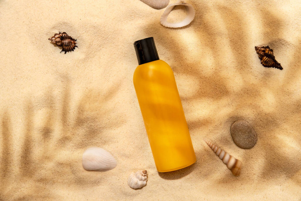 Bottle of sunscreen lotion on the sandy beach. Skin care and protection concept. Golden tan. - Фото, зображення