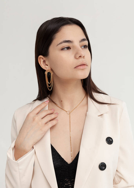 portrait of a beautiful brunette in a white jacket with massive earrings - Foto, immagini