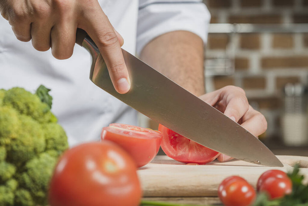 シェフは鋭いナイフボードでトマトを切る男だ。解像度と高品質の美しい写真 - 写真・画像