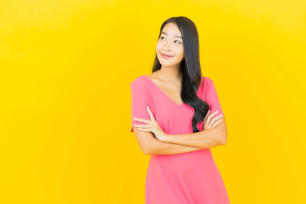Asyalı güzel bir kadının portresi. Sarı arka planda hareketli gülümsüyor. - Fotoğraf, Görsel