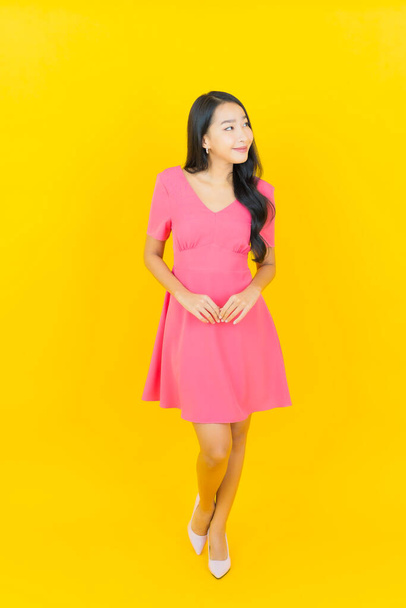 Portrait beautiful young asian woman smile with action on yellow color background - Photo, image