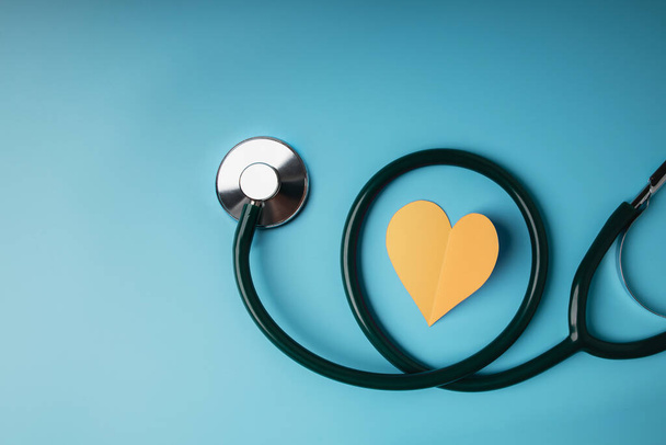 Koncepcja opieki zdrowotnej. Międzynarodowy Światowy Dzień Serca. Paper Cut as Heart Shape with Stethoscope leżał na niebieskim tle. Życie, miłość i troska. Widok z góry - Zdjęcie, obraz