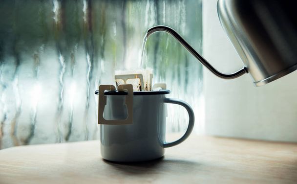 Dripping Coffee by the Window no Morning Rainy Day. Fazendo bebida quente derramando água quente da chaleira em um saco de gotejamento de café instantâneo. Relaxando, desfrutando com Harmony Living Lifestyle - Foto, Imagem