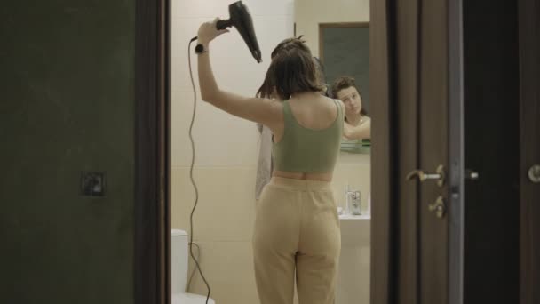 Lány szárítja a hajat hajszárítóval a fürdőben. - Felvétel, videó