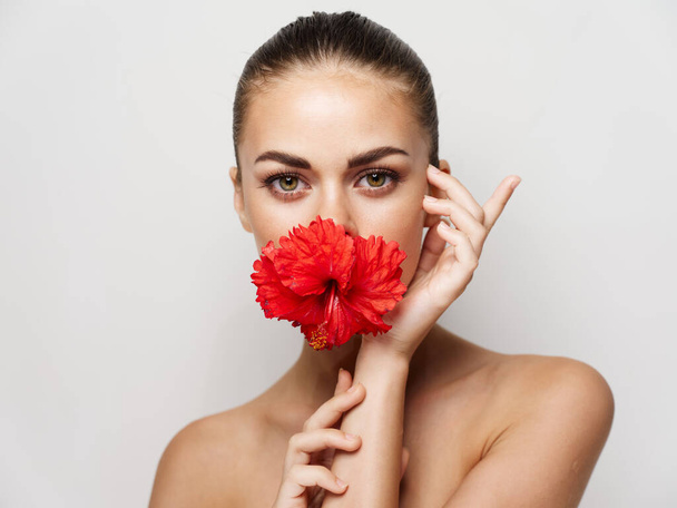 bonita mujer con flor roja en su boca hombros desnudos de cerca - Foto, Imagen