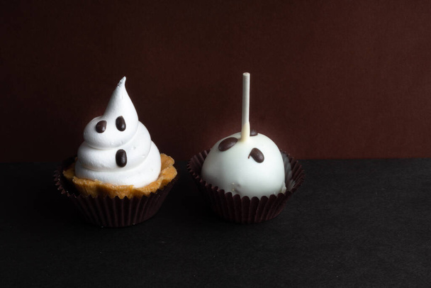 Happy homemade Halloween cupcakes treats decorated with whipped cream and chocolate. Snack of scary, ghost monster symbol for party, copy space - Photo, image